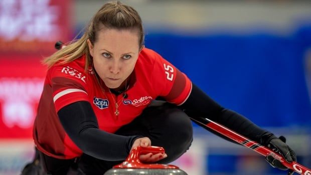 A female curler delivers a shot.