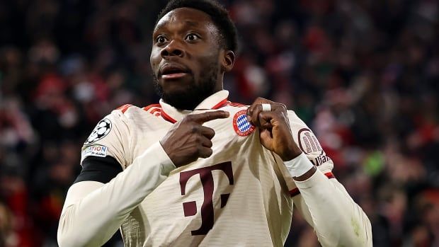 A soccer player points to the badge on his jersey.