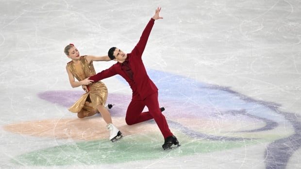 An ice dance duo kneels on the ice during a performance.