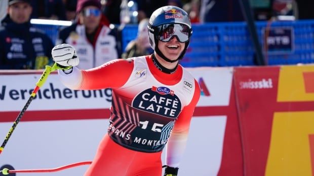 A men's alpine skier pumps his fist and smiles at the finish area.