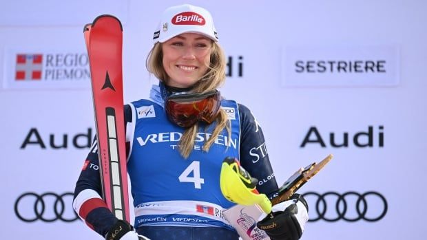 A female alpine skier smiles on the podium.