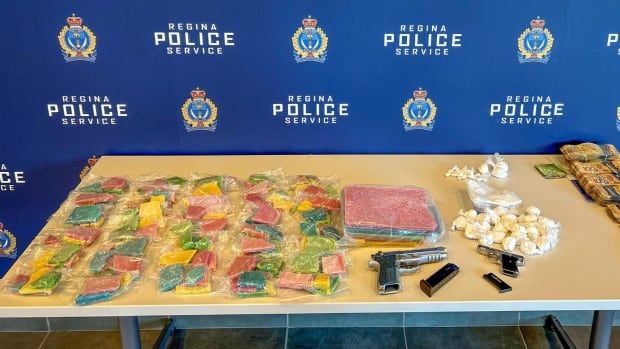 Baggies of drugs, including fentanyl, cocaine and methamphetamine are displayed on a table next to firearms and cash.