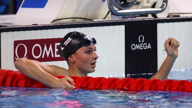 Female swimmer hangs on to floating lane divides after a race.