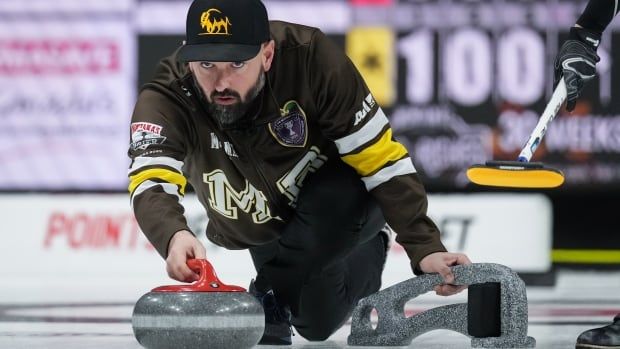 Male curler lunges down on ice to throw rock.