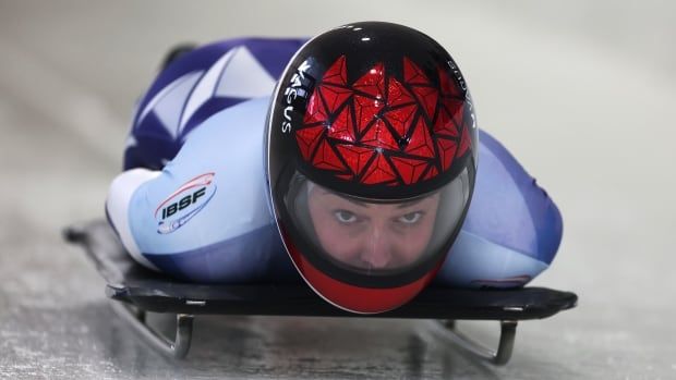 A female skeleton racer speeds down a track.