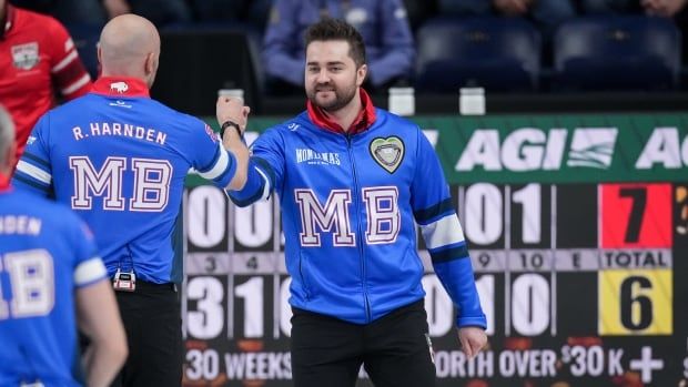 Two male curlers bump fists in celebration after a win, with the scoreboard showing a score of seven to six.