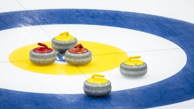 Several curling stones from opposing teams near the button.