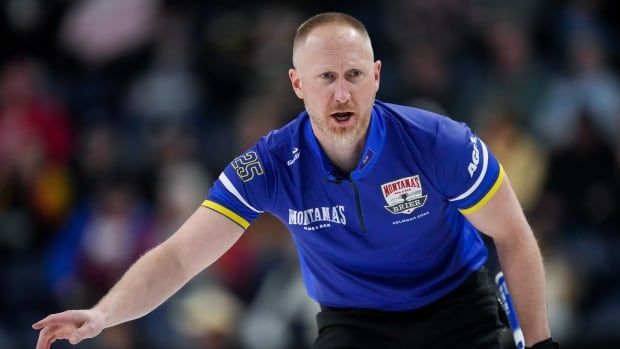 Male curler bends over with arm out as he calls out to teammates across the ice.