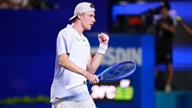 Male tennis player pumps fist at his side in celebration on the tennis court