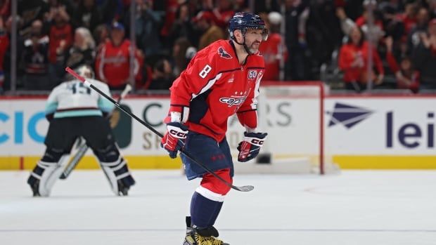 Male hockey player skates over to bench to celebrate goal