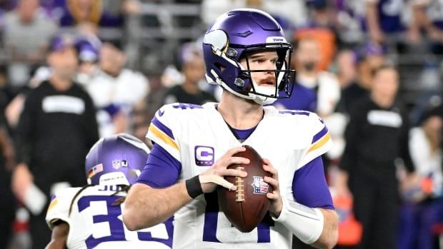 Male quarterback drops back in the pocket during a game with ball in hand.