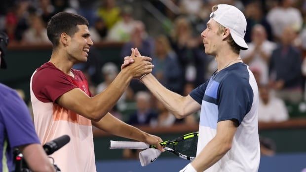 Two men's tennis players shake hands at the net.