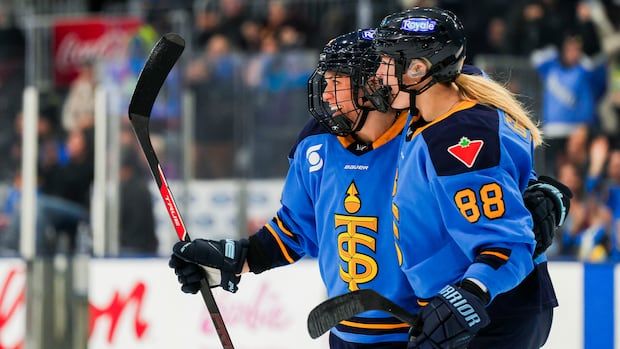 women's hockey player celebrating a goal with her teammate