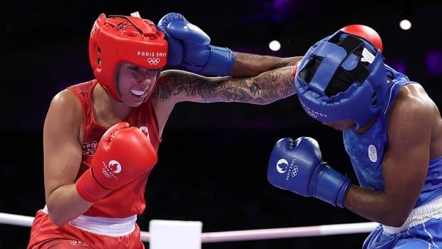 Canadian athlete Tammara Thibeault and Cindy Winner Djankeu Ngamba of Refugee Olympic Team exchange punches during the women's 75-kilogram preliminary round match at the Paris Olympic Games on July 31, 2024.