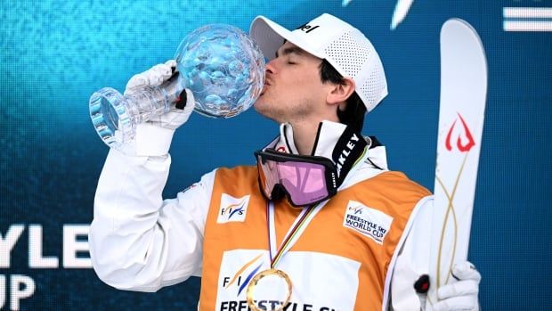 A men's skier kisses a trophy.