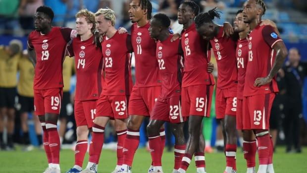 A group of soccer players stand on the field.