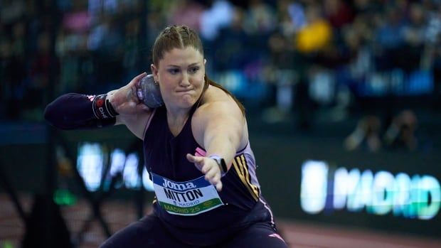 A woman throws a shot put.