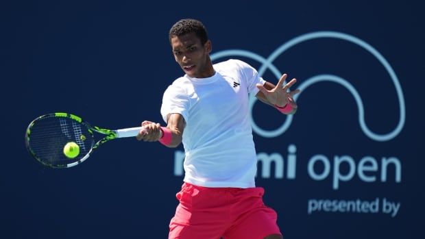 A male tennis player returns a shot with the racket in his right hand.