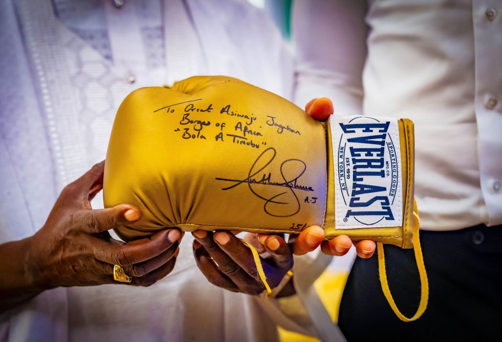 Anthony Joshua presenting President Bola Tinubu with an autographed boxing glove.